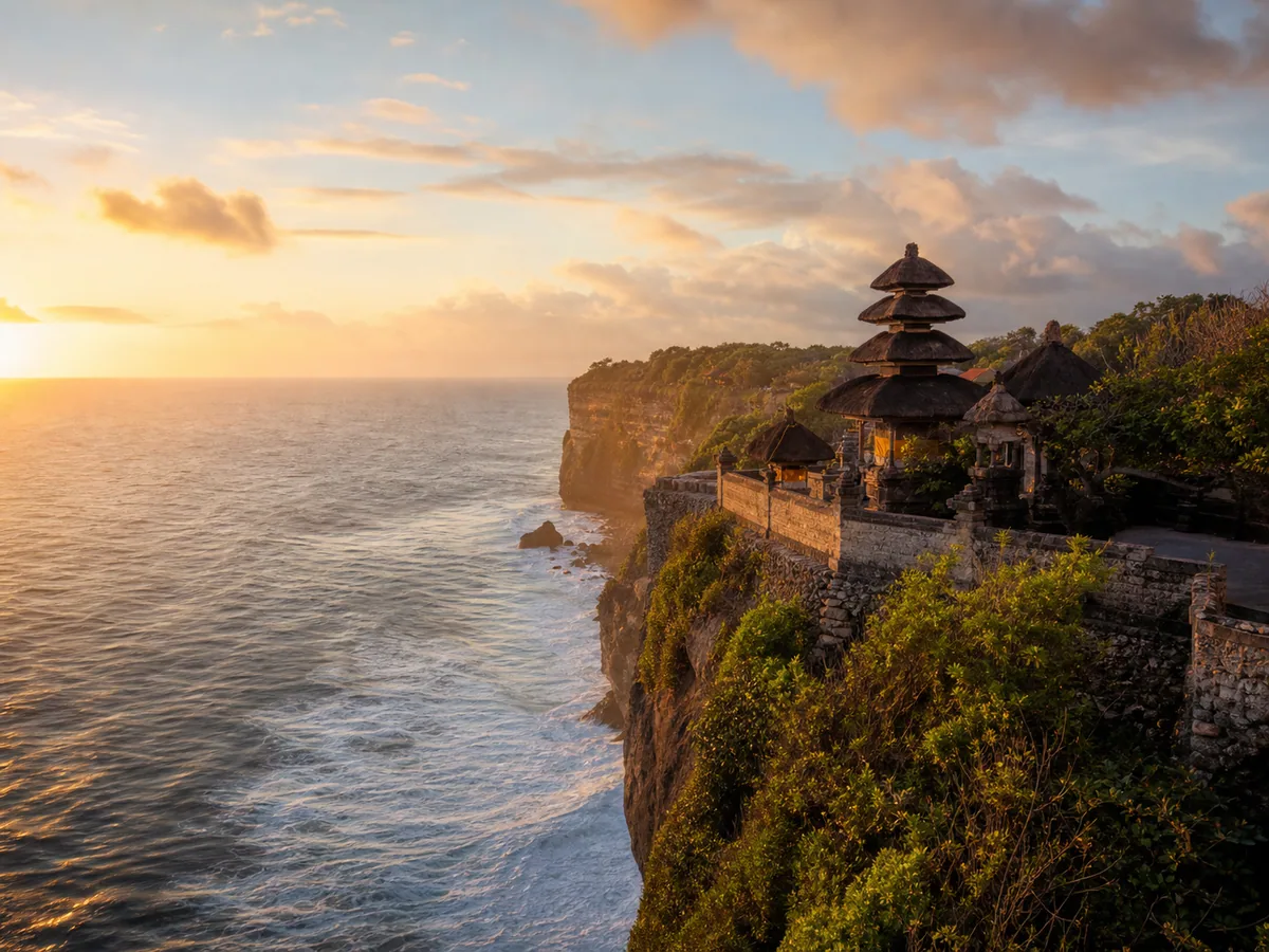 Uluwatu Temple on cliff at sunset with ocean waves below